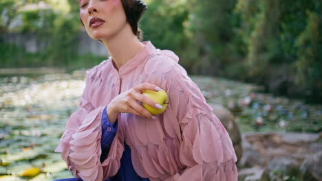 mesmerizing woman posing nature holding green apple closeup. model sitting lake