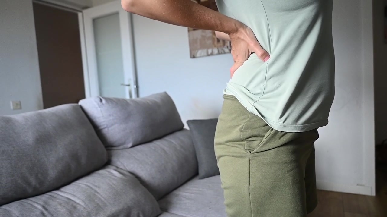 Woman getting up from sofa with back pain