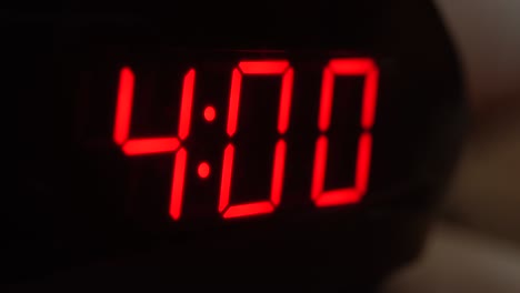 Close-up of black digital clock screen showing 4.00. Blinking red digital numbers on black background. Modern timer system and neon light, electric alarm device