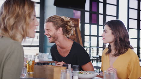 group of young friends meeting for drinks and food in restaurant