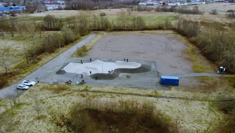 Skaters-Having-Fun-At-The-Skatepark-In-Kållered,-Mölndal,-Sweden---aerial-trucking-shot