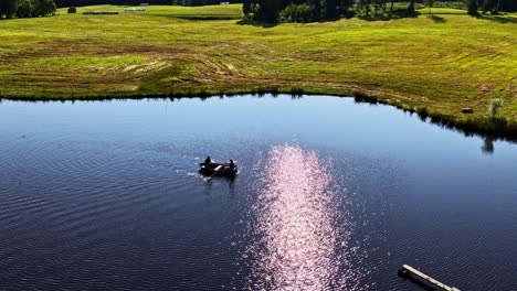 aerial of couple rowing in a small pond on a sunny countryside day