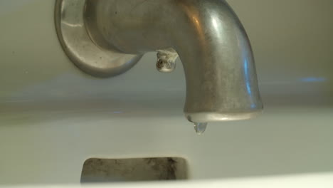 Medium-shot-of-a-faucet-as-the-water-runs,-is-turned-off-and-drips