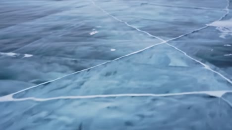 melting ice creates intricate designs on a frozen lake surface during the winter. the stunning blue hues reflect the clear sky and water, showcasing nature's artistry.