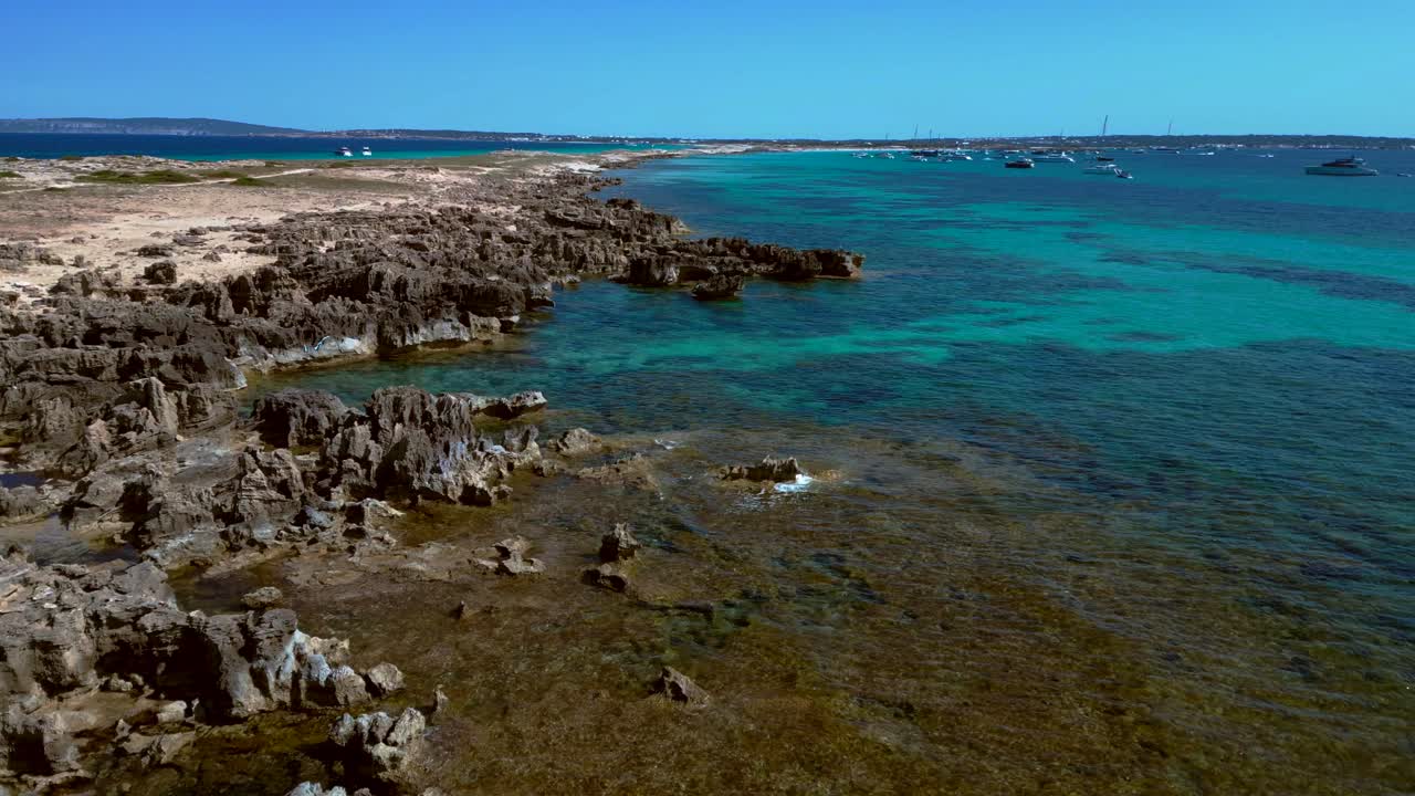 Punta des Borronar beach on Formentera Ibiza island with yachts mooring in clear turquoise water. Nice aerial view flight static tripod hovering drone