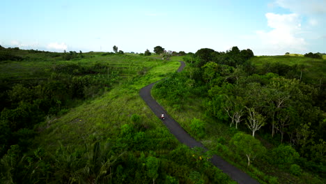 girl in white drives scooter uphill while exploring teletubbies hills, bali