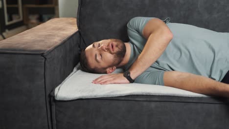 un hombre cansado cae exhausto en el sofá y se queda dormido