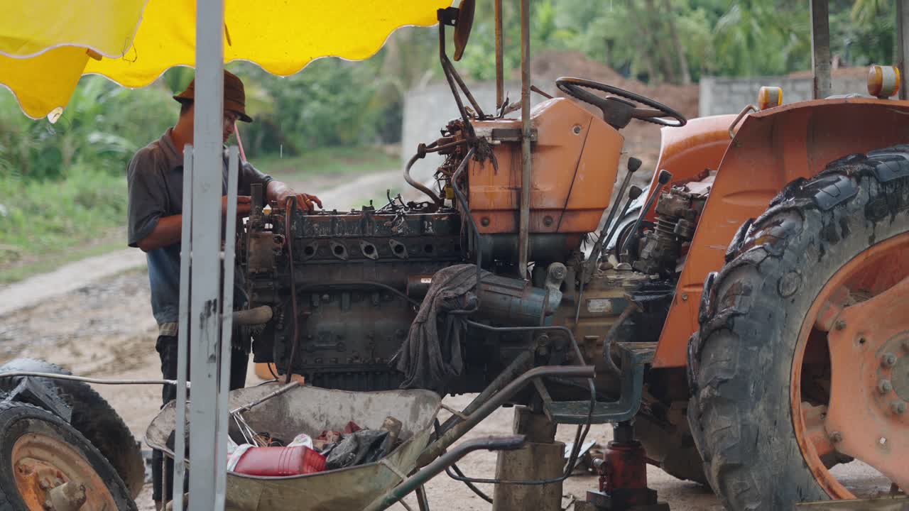 Farmer repairing tractor engine