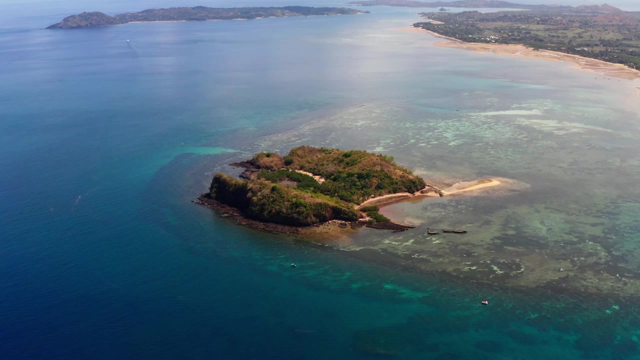 Vista aerea con drone dell'isola di Nosy Be in Madagascar durante una giornata di sole; l'oceano blu e la costa della spiaggia riflettono le nuvole a Palm Beach. Nosy Tanga e Nosy Sakatia nell'inquadratura.