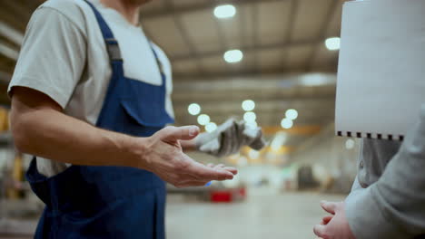 close-up of factory worker and engineer shaking hands and talking