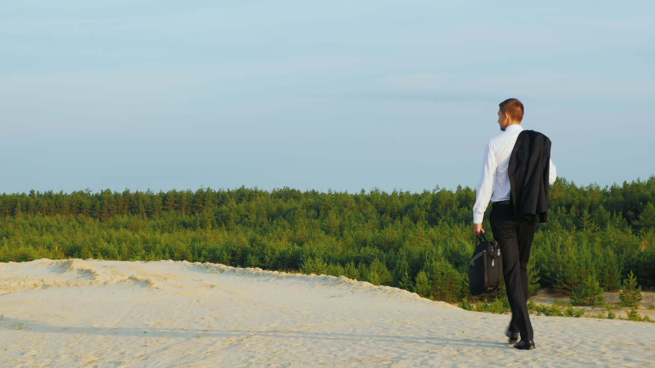 케이스를 손에 든 사업가가 모래사장을 걷고 있다 3