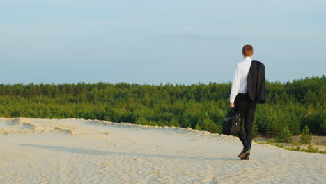 a businessman with a case in his hand walks along a sandy beach 3