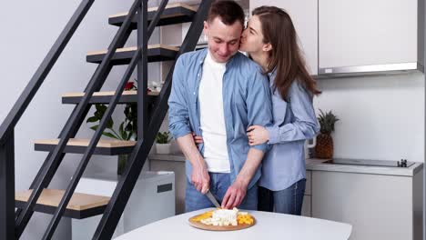 una pareja preparando un plato de queso y frutas en la cocina