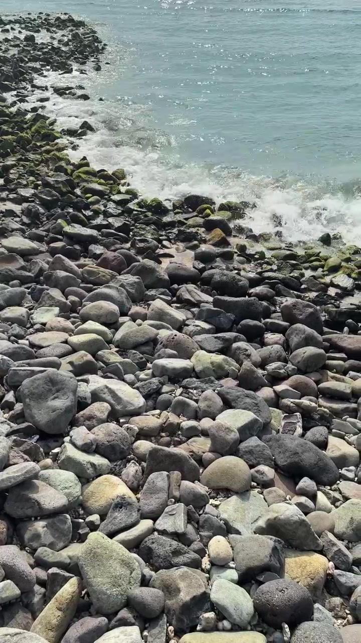 Onde delicate che lambiscono una spiaggia rocciosa di ciottoli.