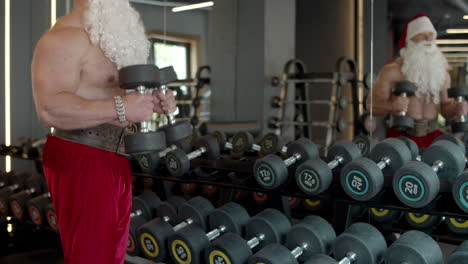 hombre fuerte de santa haciendo flexiones de bíceps en el gimnasio. entrenamiento de deportista en club deportivo