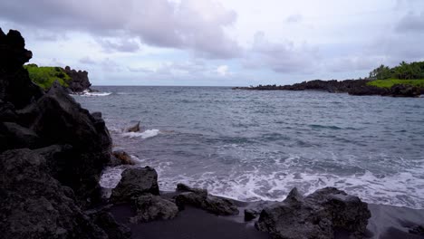 hawaiian black sand beach in waianapanapa state park along the road to hana in east maui, hawaii, a popular tourist destination along the road to hana