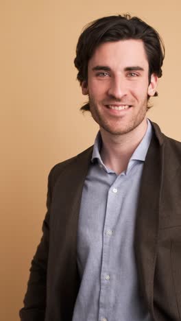 smiling man in jacket looking at camera in brown studio