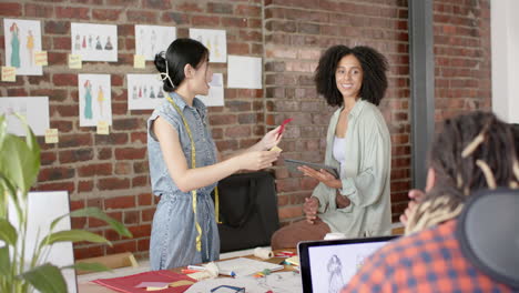 diseñadores diversos ocupados discutiendo el trabajo en el estudio de diseño de moda en cámara lenta