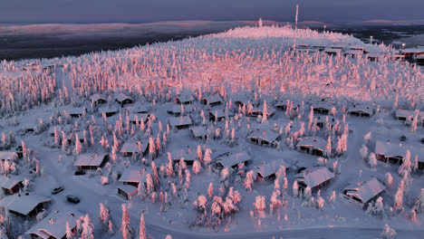 aerial tracking shot of cabins on top of the iso-syöte fell, winter sunrise in finland