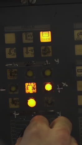 close-up of an industrial control panel with illuminated buttons and operator hand