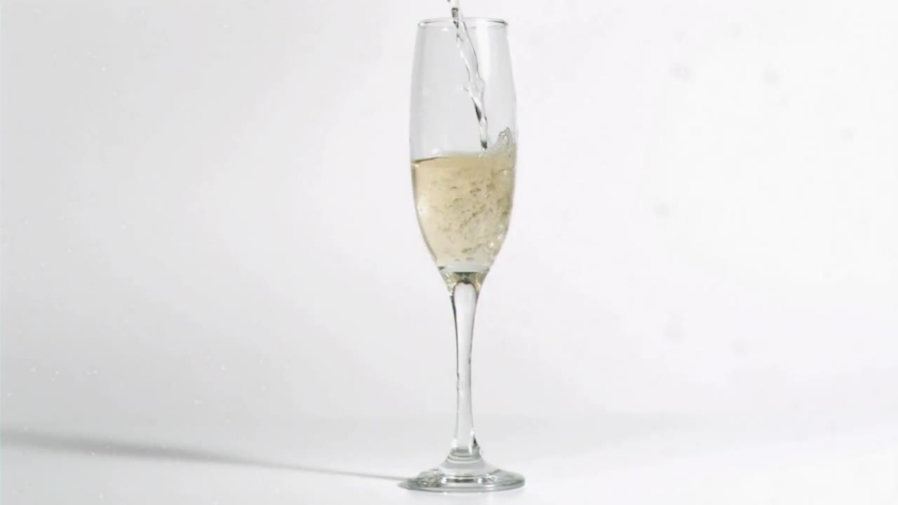 Animation of white specks falling over glass of champagne on white background