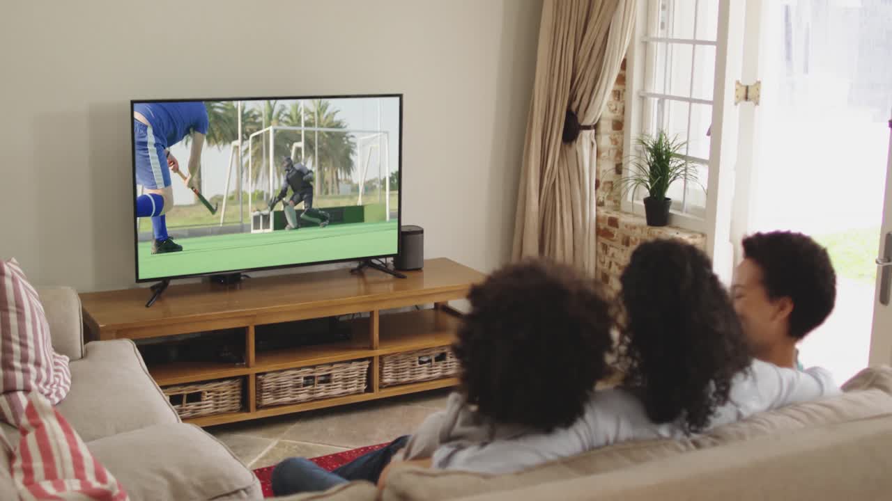 Famiglia felice seduta a casa insieme che guarda una partita di hockey in TV