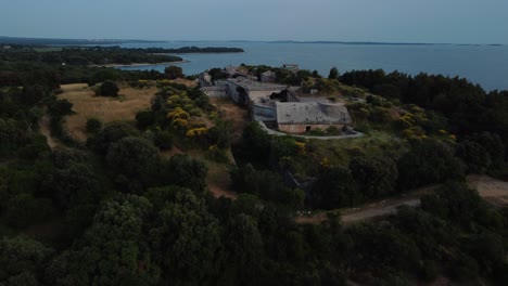 Drone-De-Vista-Aérea-Cinematográfica-Sobre-Una-Fortificación-Histórica-De-La-Fortaleza-Costera-De-La-Primera-Guerra-Mundial-Junto-Al-Idílico-Mar-Mediterráneo-Adriático-Con-Agua-Azul-Y-Playas-Escondidas-Al-Atardecer-En-Verano