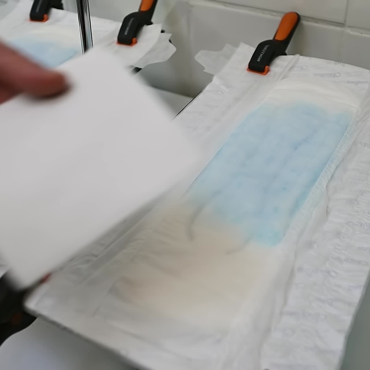 Researcher's hand checking the absorption of the inner layer in diaper with his finger. Male hand presses the napkin to the diaper and show that it's dry. Close up