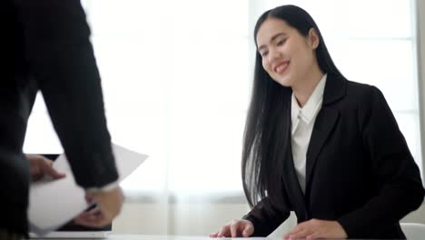 smart asian woman shakes hands to greet a hr staff before a job interview to apply for a job. happy woman seeker or insurance broker presenting a business deal. business woman sending resume.