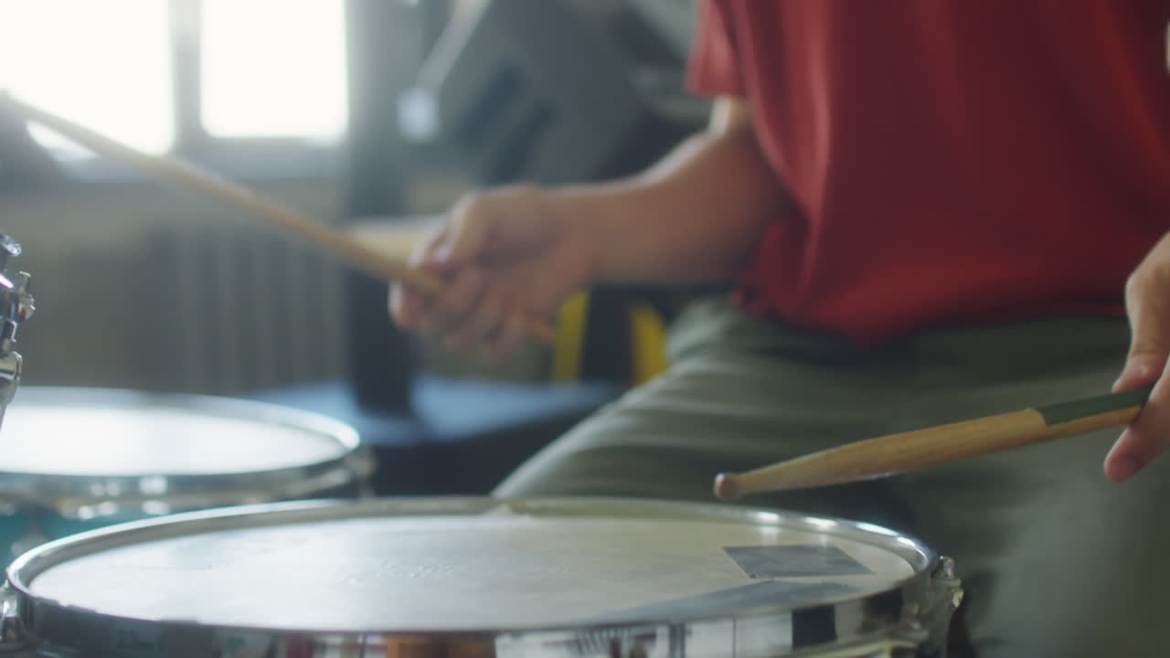 Close-up of a Person Playing Drums with Drumsticks