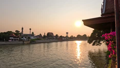 sun setting behind a peaceful riverside community