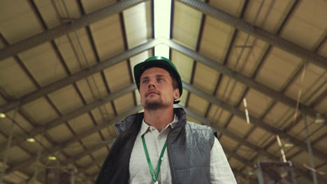 confident man walking shed in helmet. livestock owner inspecting cowshed work.