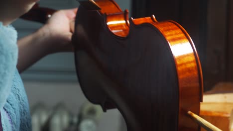mano de un luthier fabricante de violines barnizando un instrumento de cuerda de madera hecho a mano
