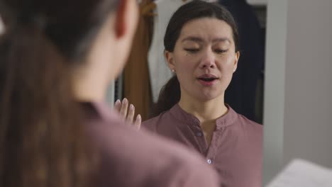 young woman in home practising job interview technique reflected in mirror 3