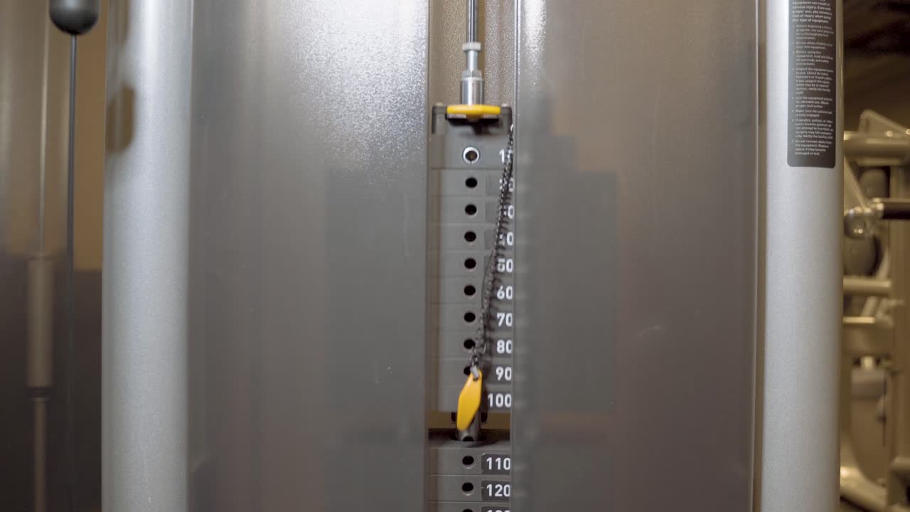 운동하는 동안 체육관에서 위아래로 들어 올리는 케이블 운동 기계의 웨이트 스택 플레이트