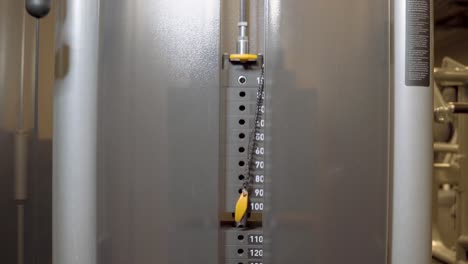 placas de pila de peso en la máquina de ejercicio por cable levantando y bajando en el gimnasio durante el entrenamiento