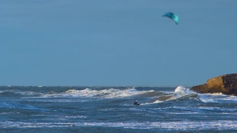 a group of people engaged in kitesurfing in sunny autumn day, high waves, baltic sea karosta beach in liepaja, medium shot