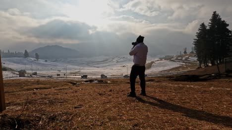 indian person taking a photo of snow mountains with sun rays and nature at gulmarg, jammu and kashmir, new delhi, india. day time, stable shot, 4k.