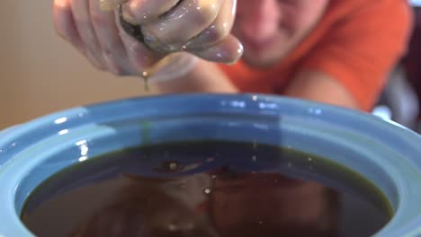 persona caucásica exprimiendo el contenido de la bolsa de té en la olla - primer plano