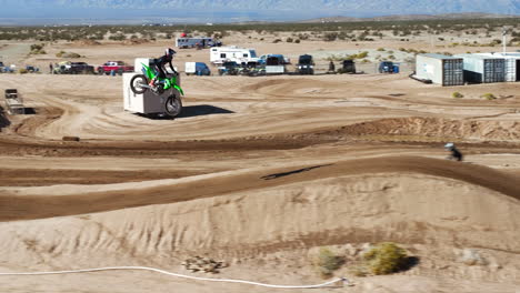 motorcycles racing on an off-road track with high jump ramps - aerial follow