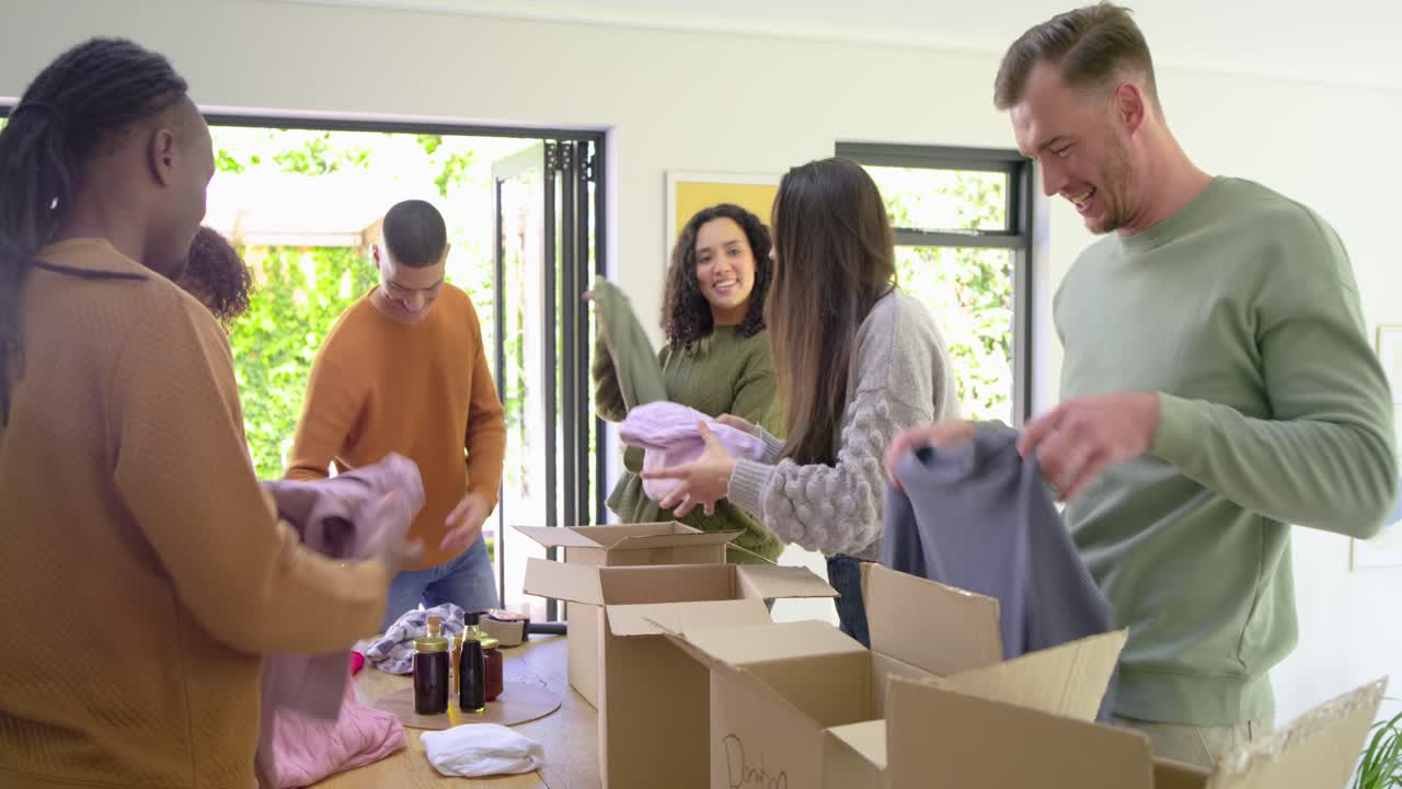 Diverse volunteers sorting and packing donation boxes as they passing basketball at dining table