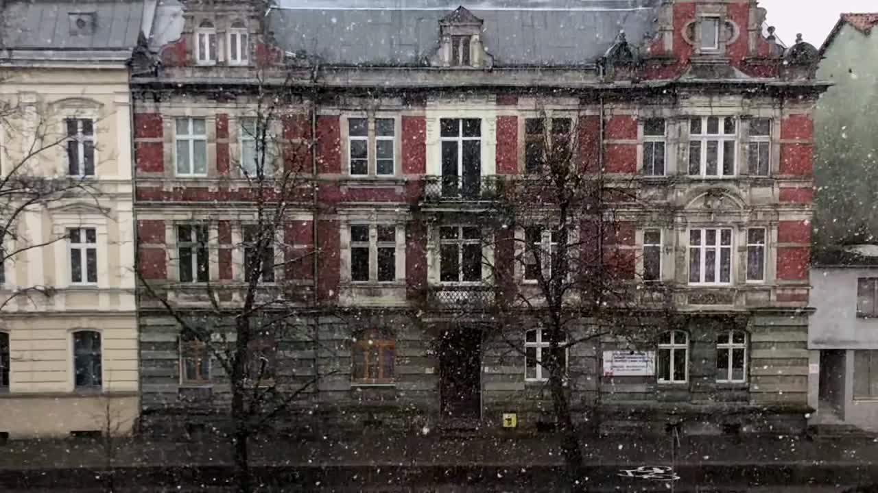 Vista ravvicinata della neve che cade su uno sfondo di edifici invernali
