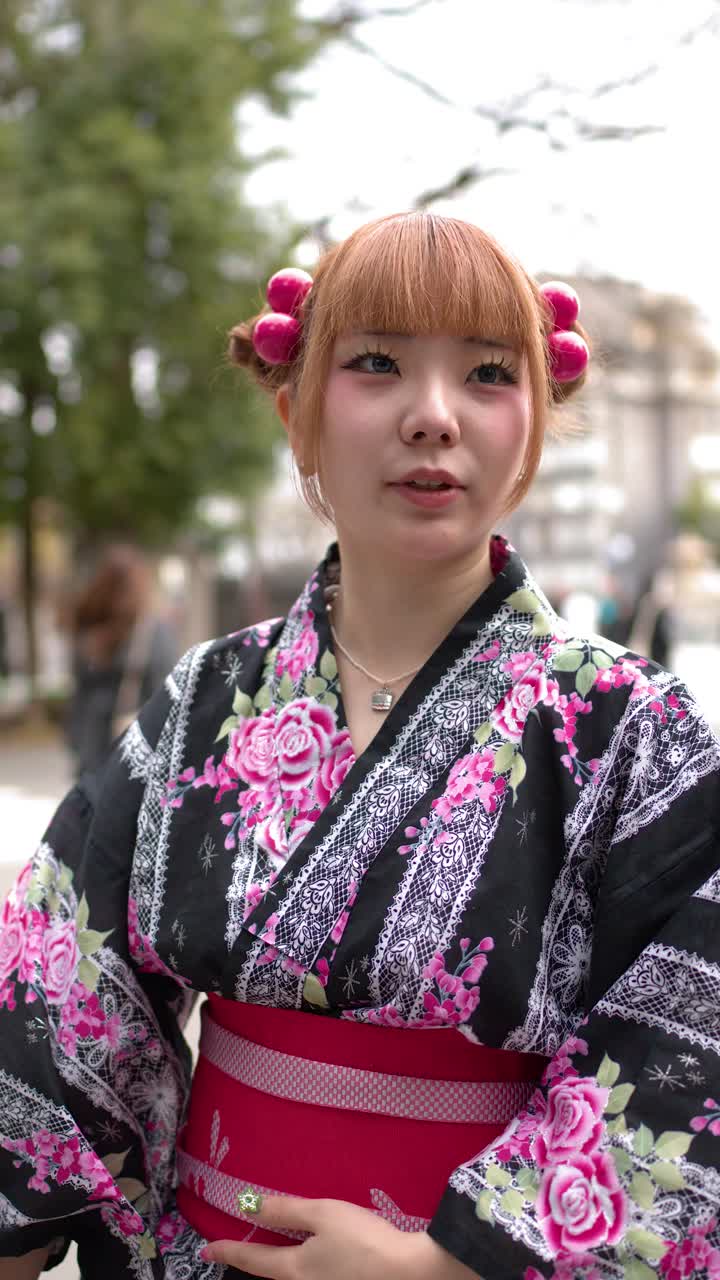 Una giovane donna che indossa un yukata floreale tradizionale sta all'aperto in una giornata luminosa.