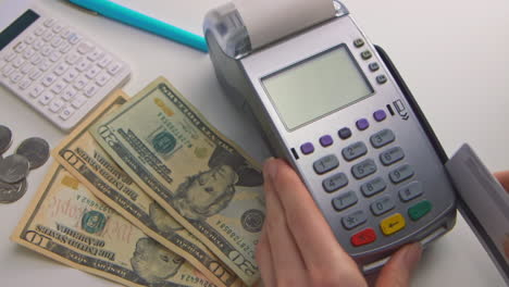 a woman's hand swipes a card into a debit machine