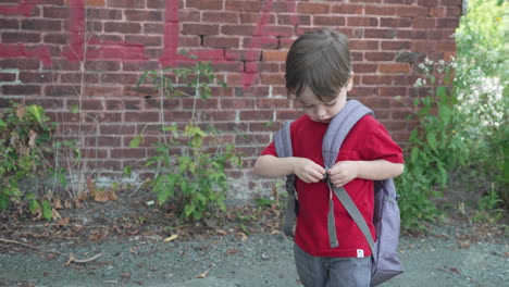 a boy adjusts the strap on his backpack in slow motion