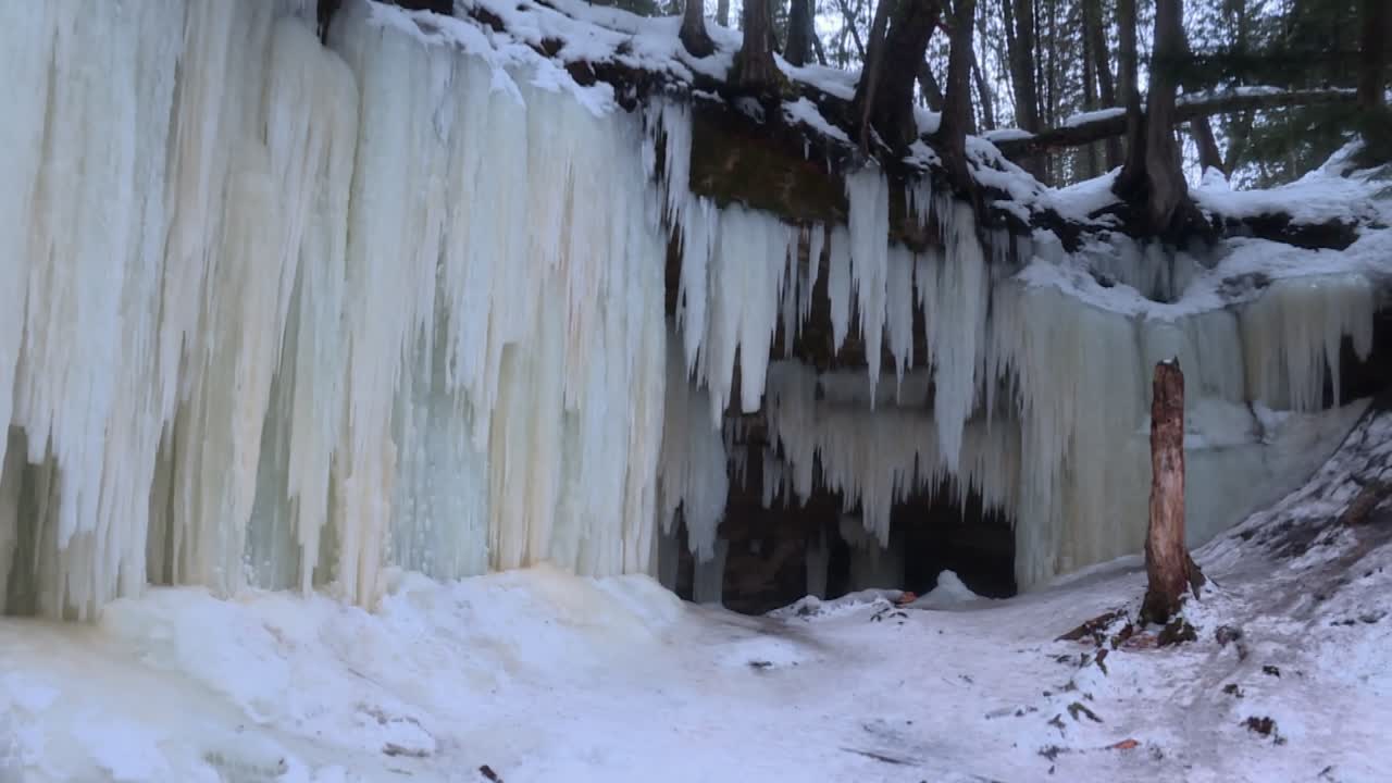 Massive frozen wall of vertical icicles cascading from a rocky ledge above the Eben Ice Caves in Michigan