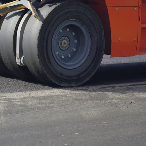 orange steamroller for asphalt with four wheels stands on the road at day