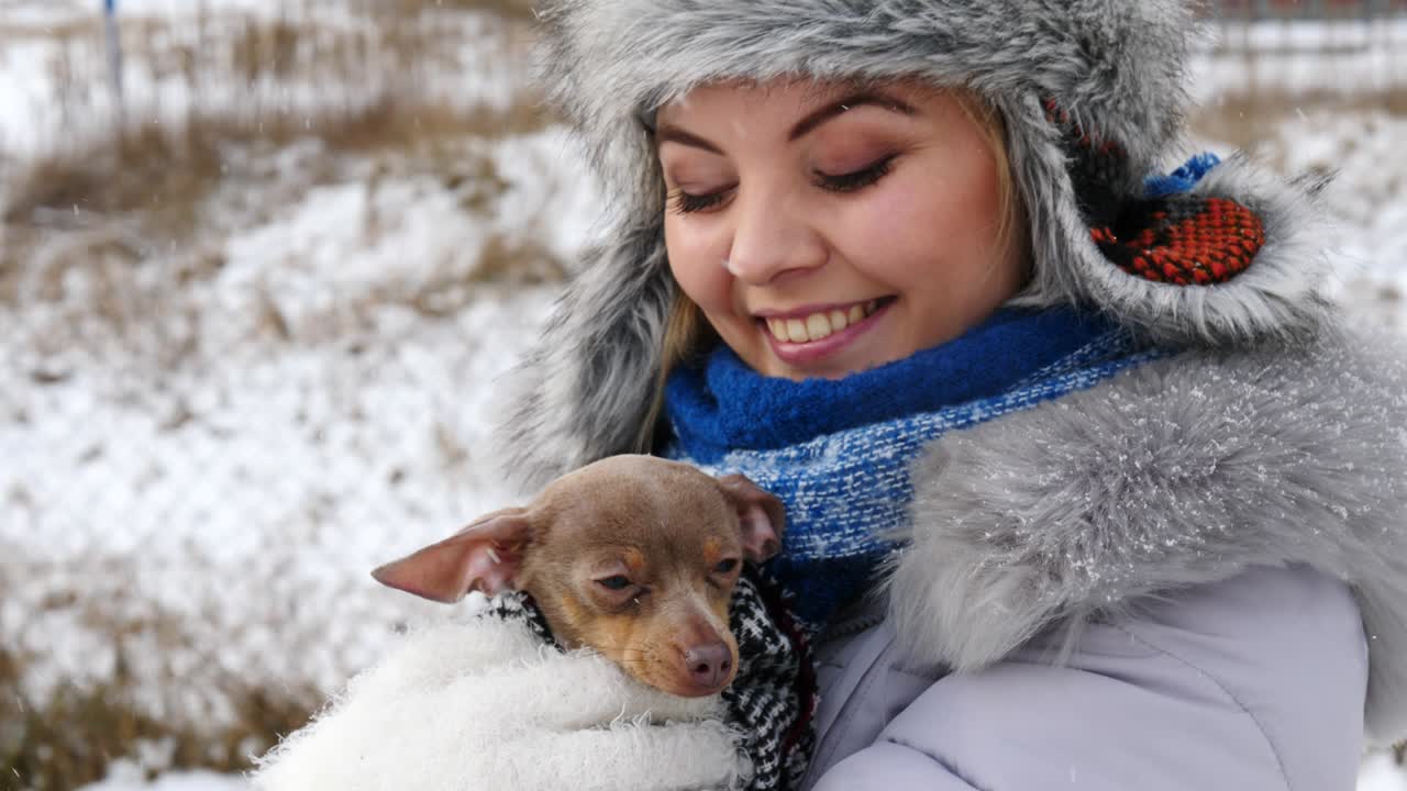 mujer jugando con su pequeño perro fuera del invierno