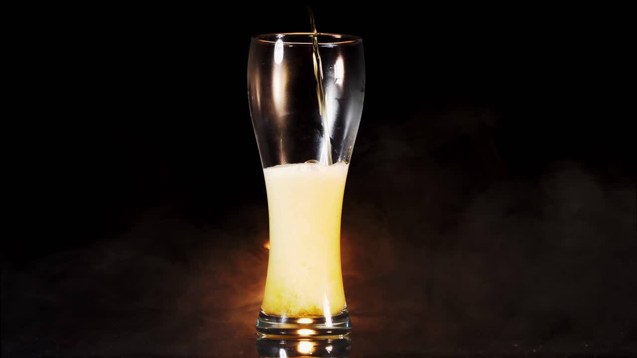 밀맥주를 바이젠 유리에 붓고, 연기가 자욱한 배경과 함께 하얀 거품이 나온다