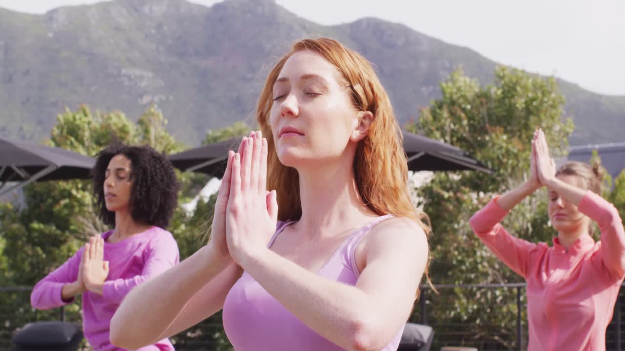 Gruppo felice di amici di diverse etnie che praticano yoga e meditano in giardino.